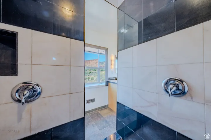 Full bath featuring tiled shower and tile walls