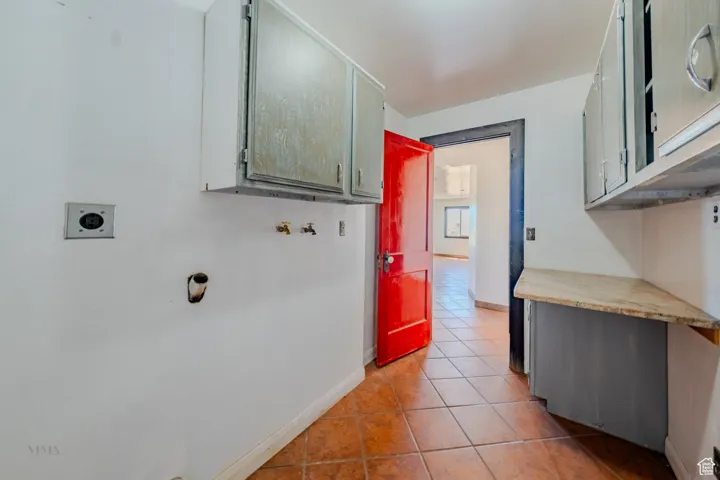 Laundry room with hookup for an electric dryer, light tile patterned floors, cabinet space, and washer hookup
