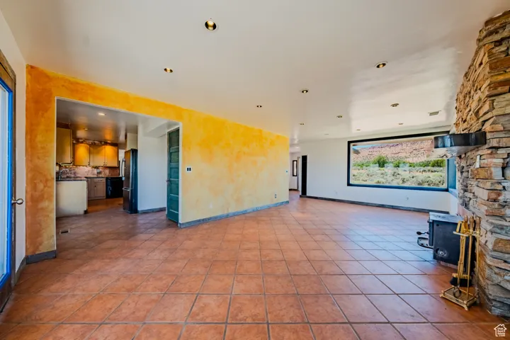 Unfurnished living room with recessed lighting, a wood stove, and tile patterned floors