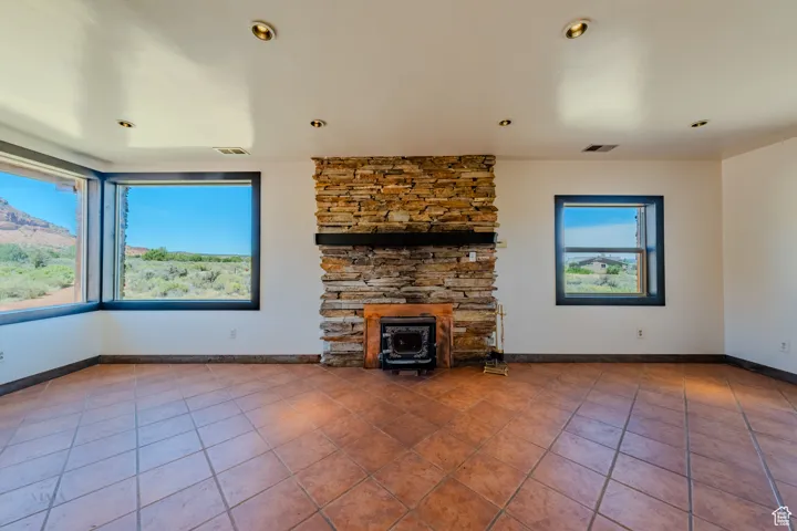 Unfurnished living room with tile patterned flooring, a wood stove, and recessed lighting