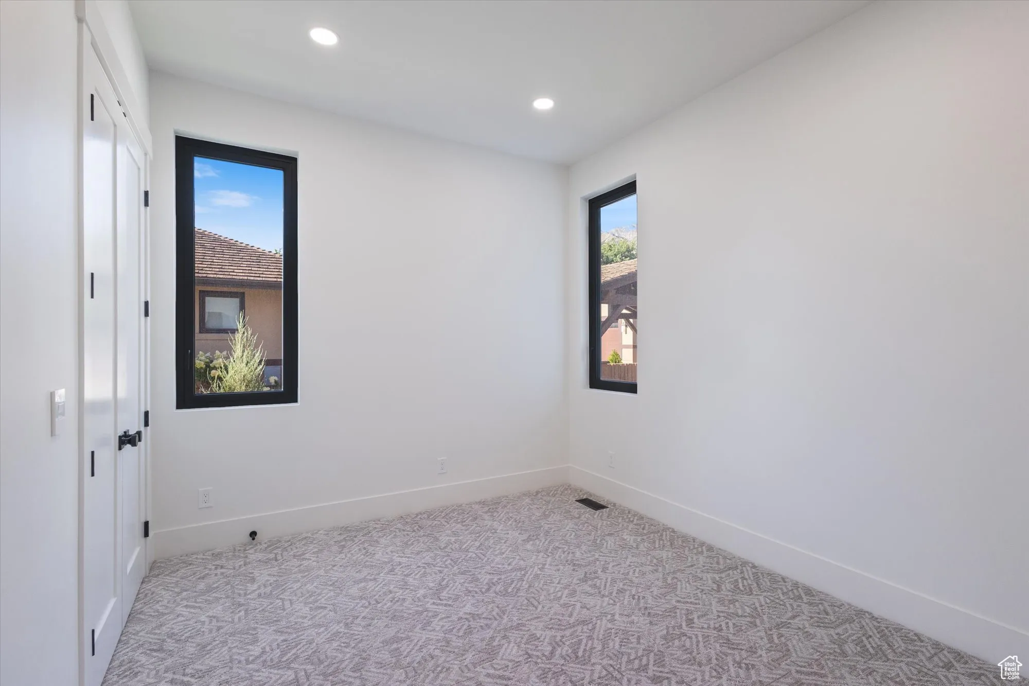 Spare room featuring light colored carpet, plenty of natural light, and recessed lighting
