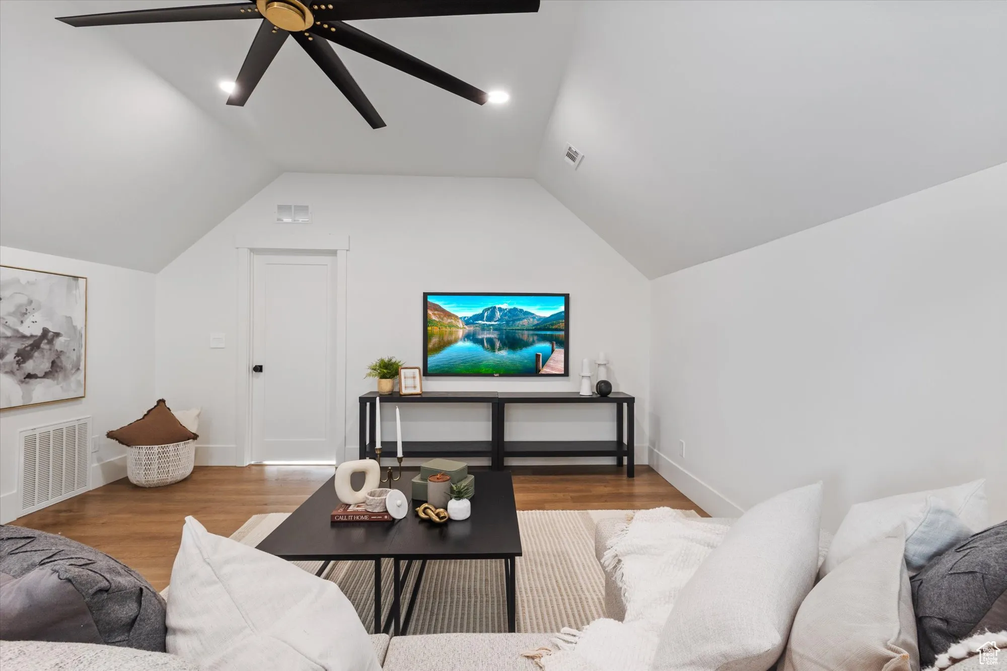 Living area featuring wood finished floors, vaulted ceiling, and ceiling fan