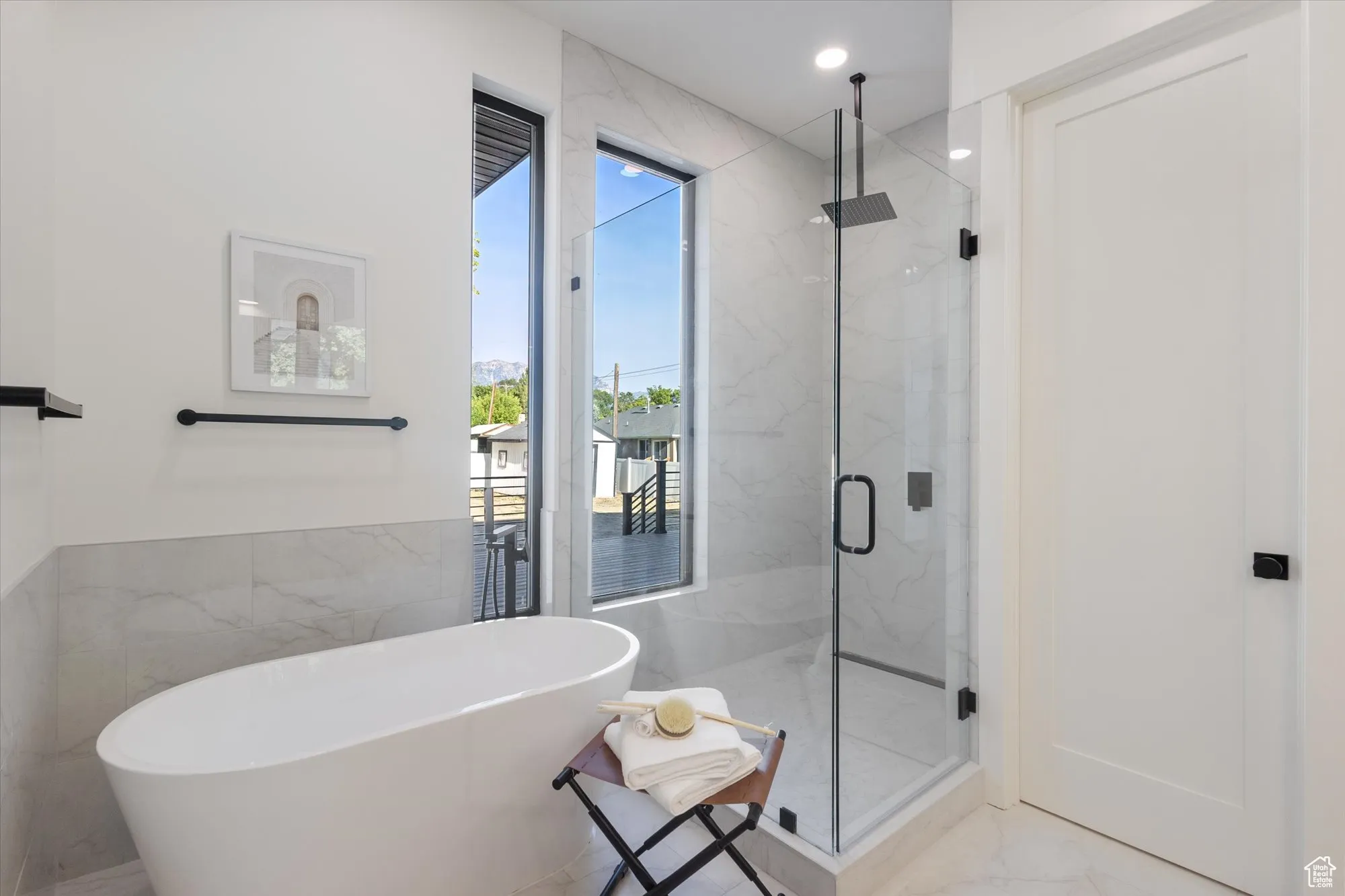Bathroom with a marble finish shower, a freestanding tub, marble finish floors, and tile walls