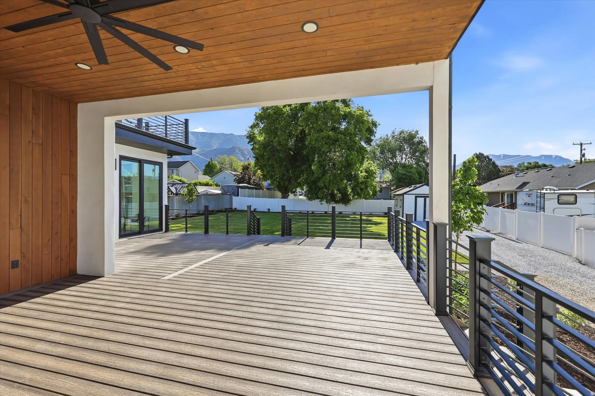 Spacious outdoor deck featuring wood-finish flooring, a wood-paneled ceiling with recessed lighting and a ceiling fan, and black horizontal railing