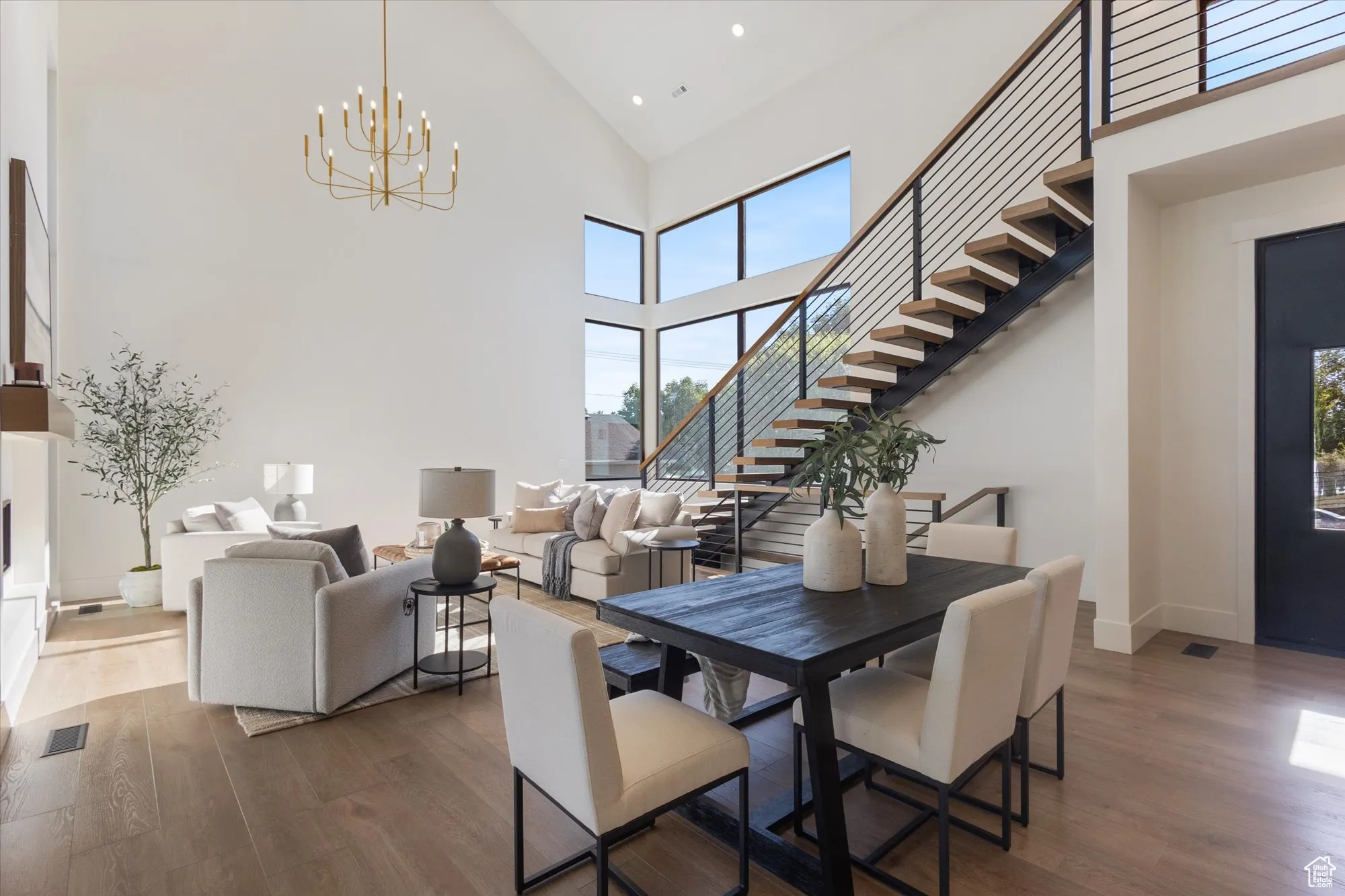 Dining room featuring wood finished floors, high vaulted ceiling, stairs, recessed lighting, and a chandelier