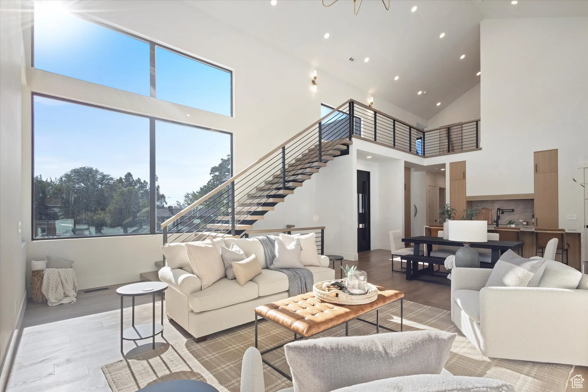 Living room featuring wood finished floors, high vaulted ceiling, stairs, and recessed lighting