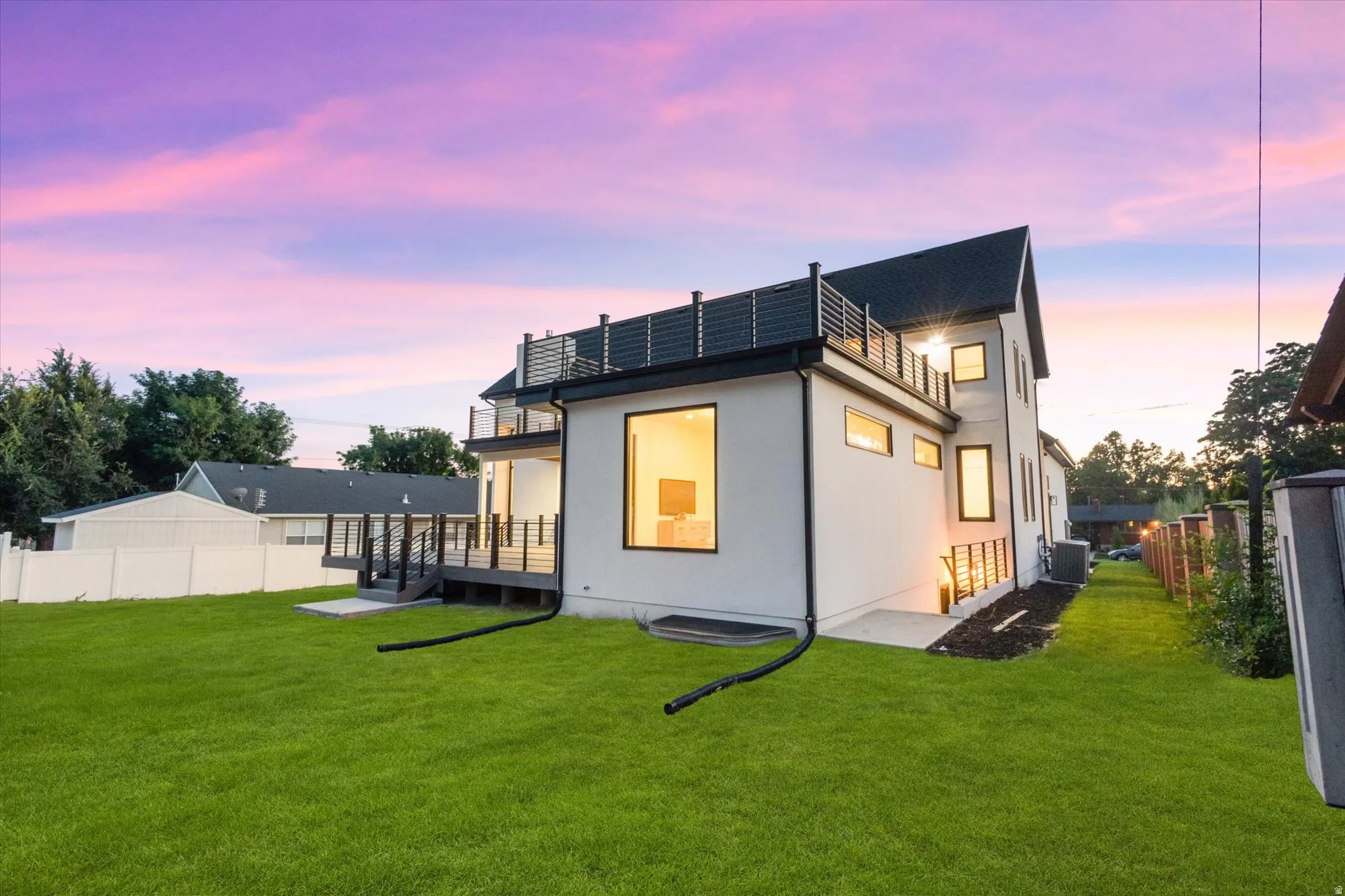 Modern architectural exterior with white siding and dark trim, featuring multiple large windows