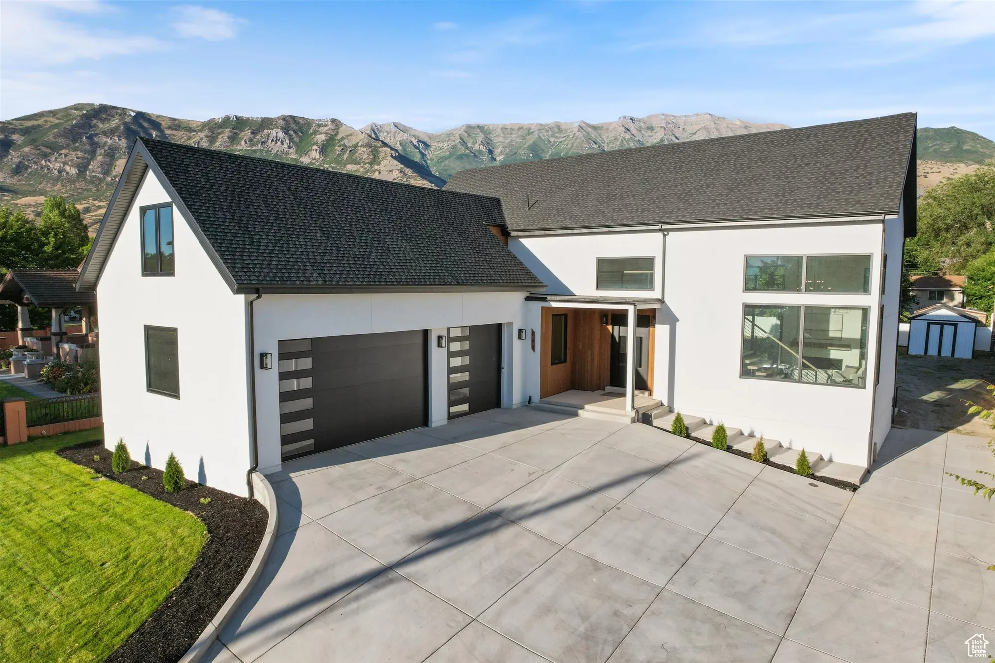 View of front of property with stucco siding, a mountain view, driveway, a garage, and a storage unit