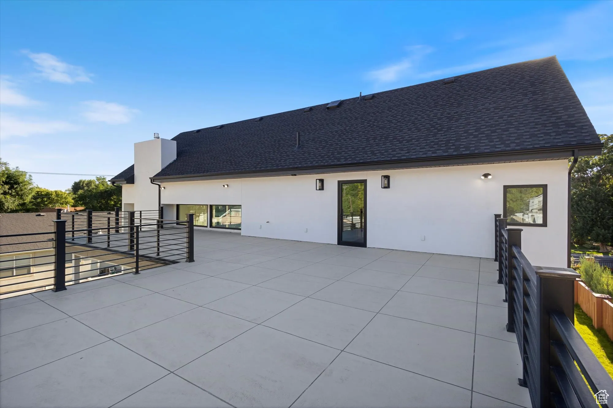 Back of property with stucco siding, a shingled roof, and a patio area
