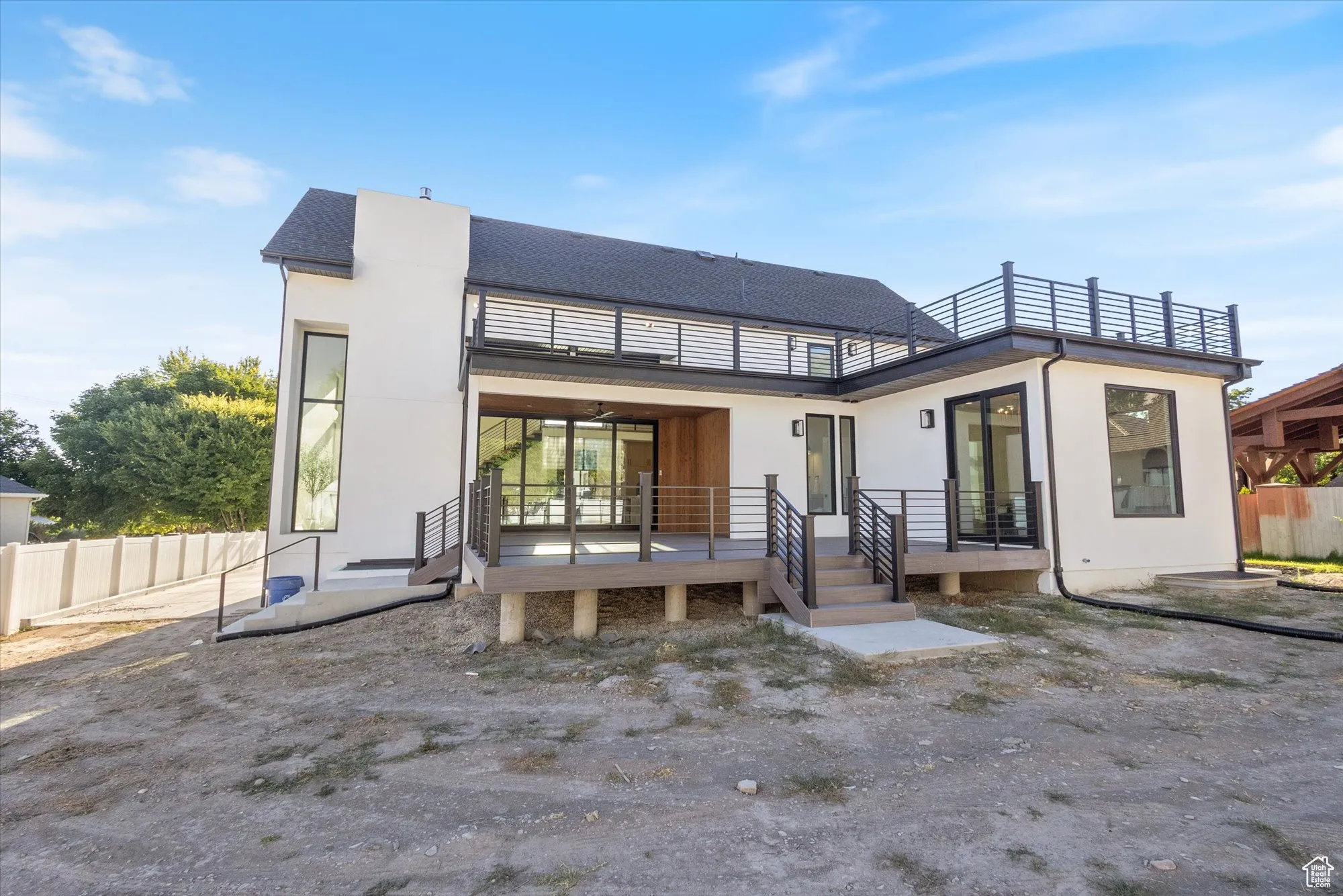 Back of property featuring a balcony, stucco siding, and a wooden deck