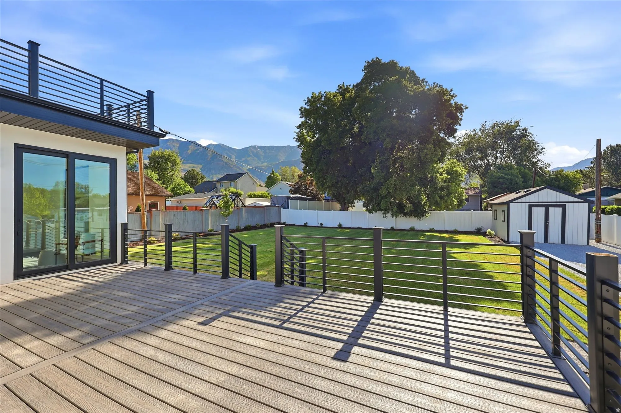 Expansive composite deck with metal cable railing, offering access to a spacious lawn