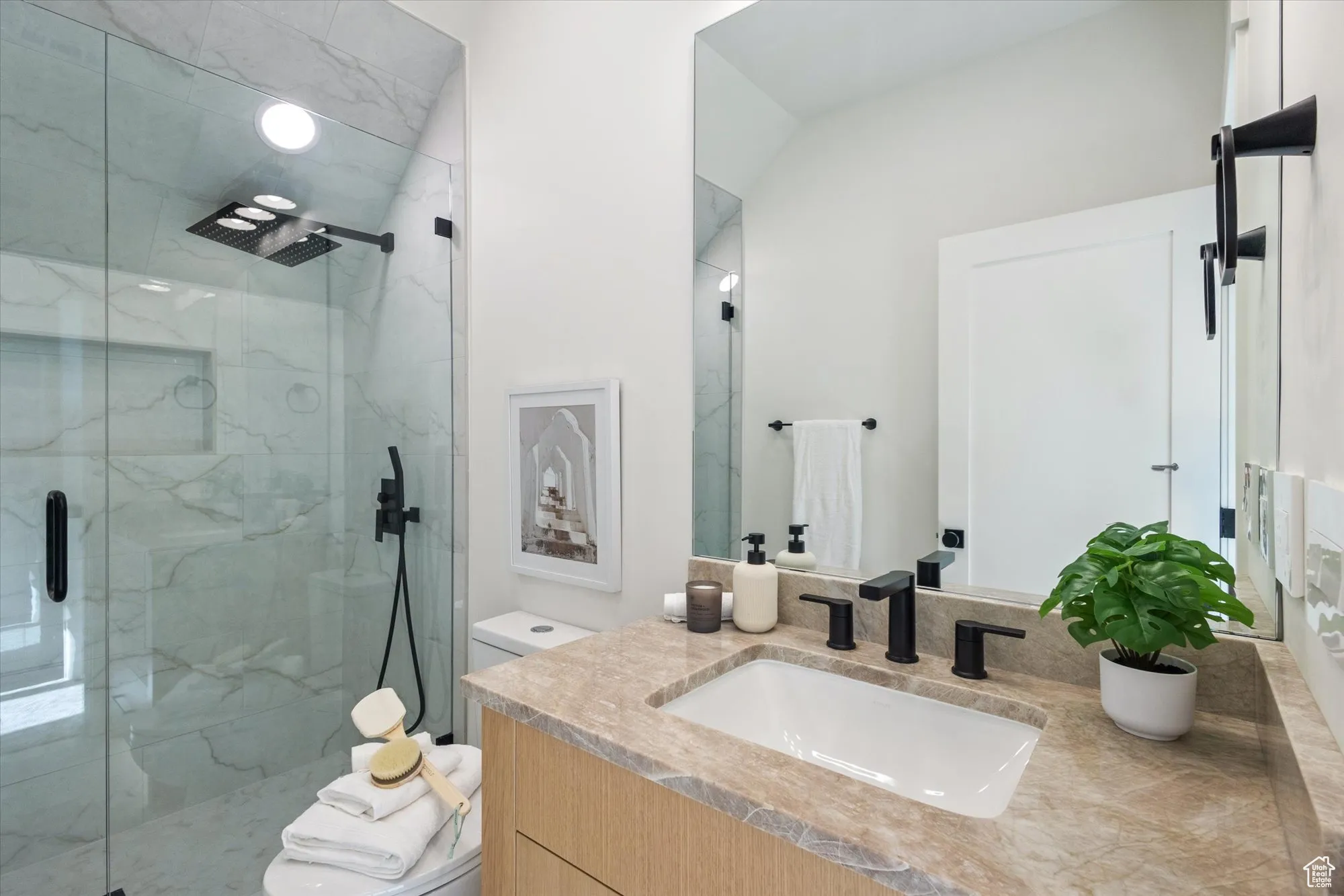Bathroom featuring a marble finish shower and vanity