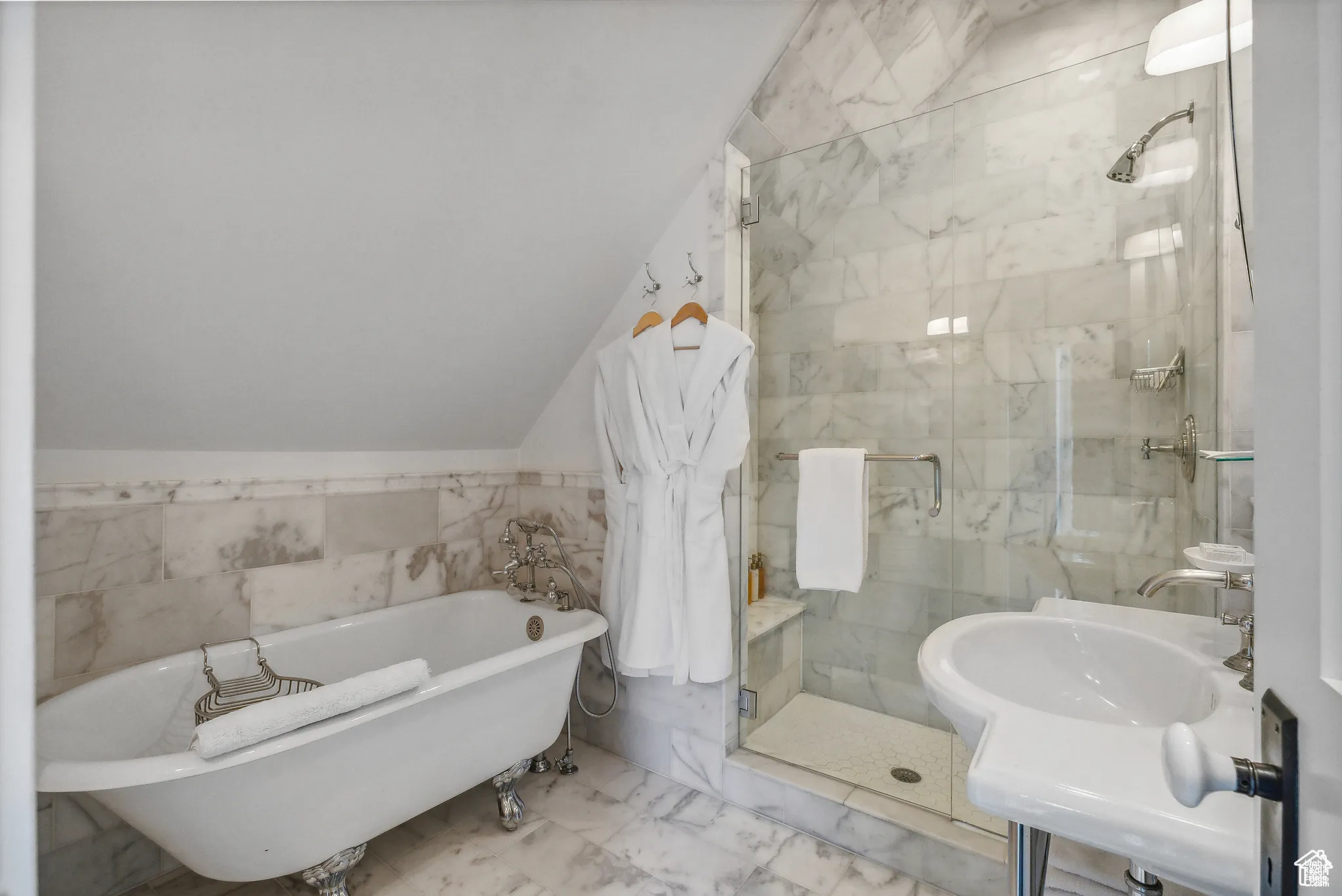 Full bath with tile walls, a shower stall, a soaking tub, marble look tile flooring, and vaulted ceiling