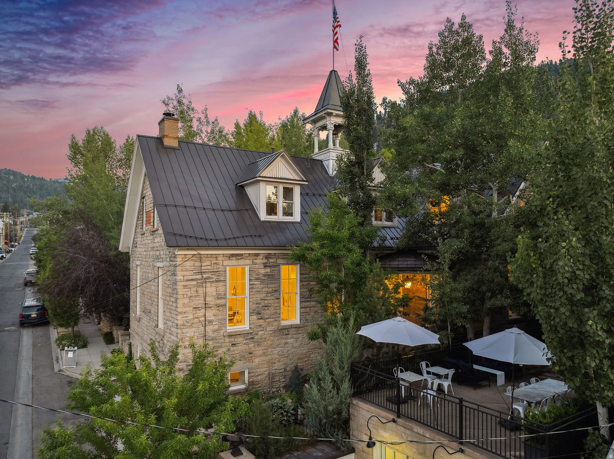 View of side of home with stone siding, a chimney, a standing seam roof, and a patio