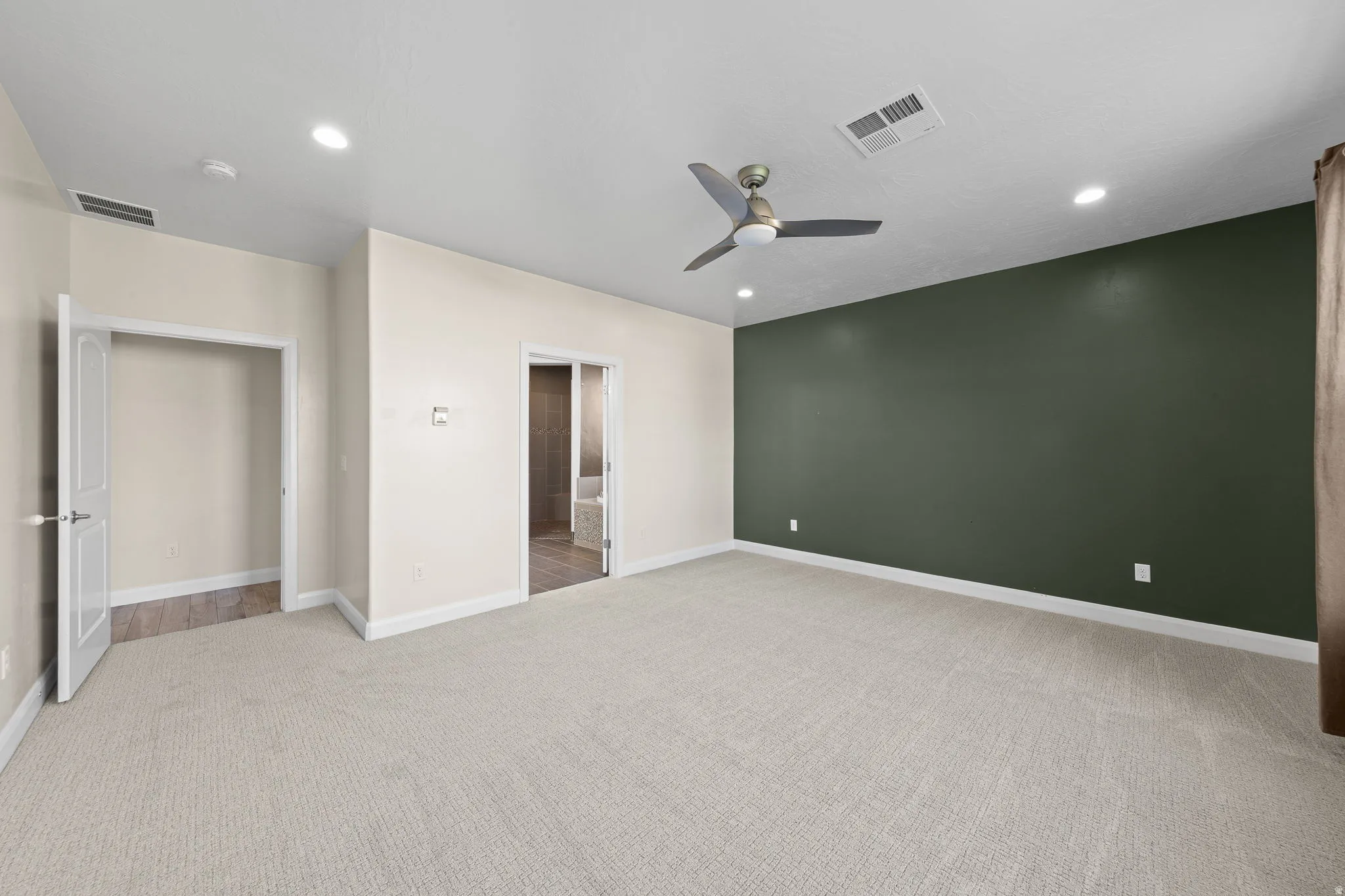 Unfurnished bedroom featuring light carpet, ceiling fan, recessed lighting, and ensuite bath