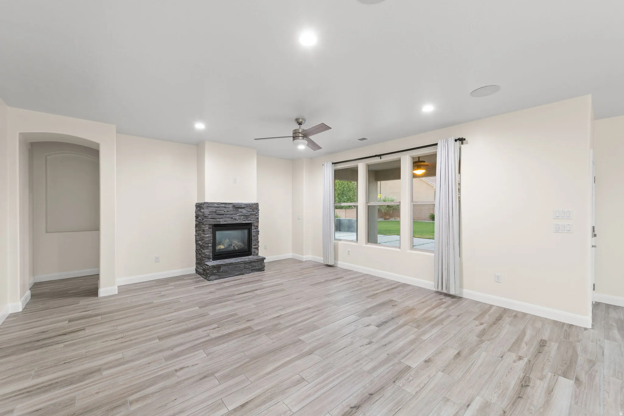 Unfurnished living room featuring light wood-style flooring, recessed lighting, a fireplace, and a ceiling fan