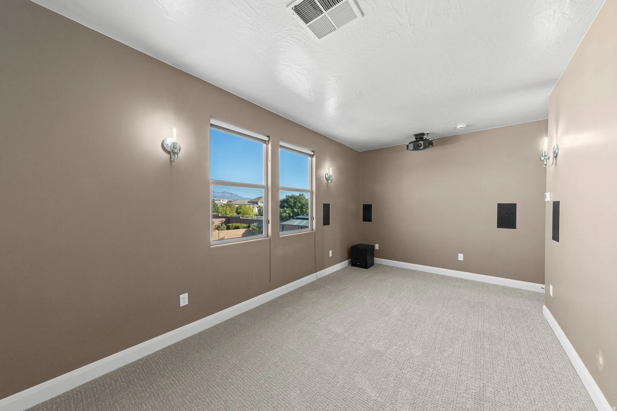 Home theater room with light colored carpet and a textured ceiling