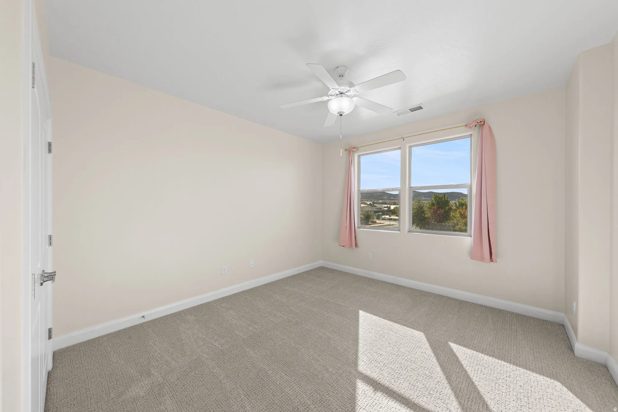 Carpeted empty room featuring baseboards and a ceiling fan