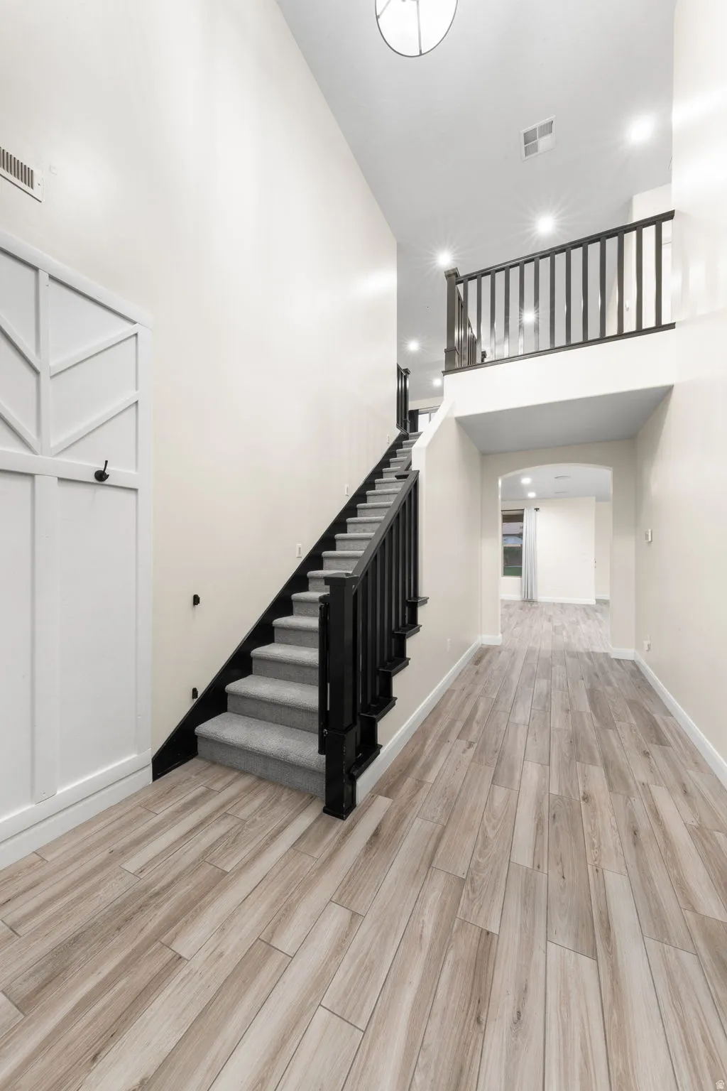 Stairs featuring wood finished floors, recessed lighting, and a high ceiling