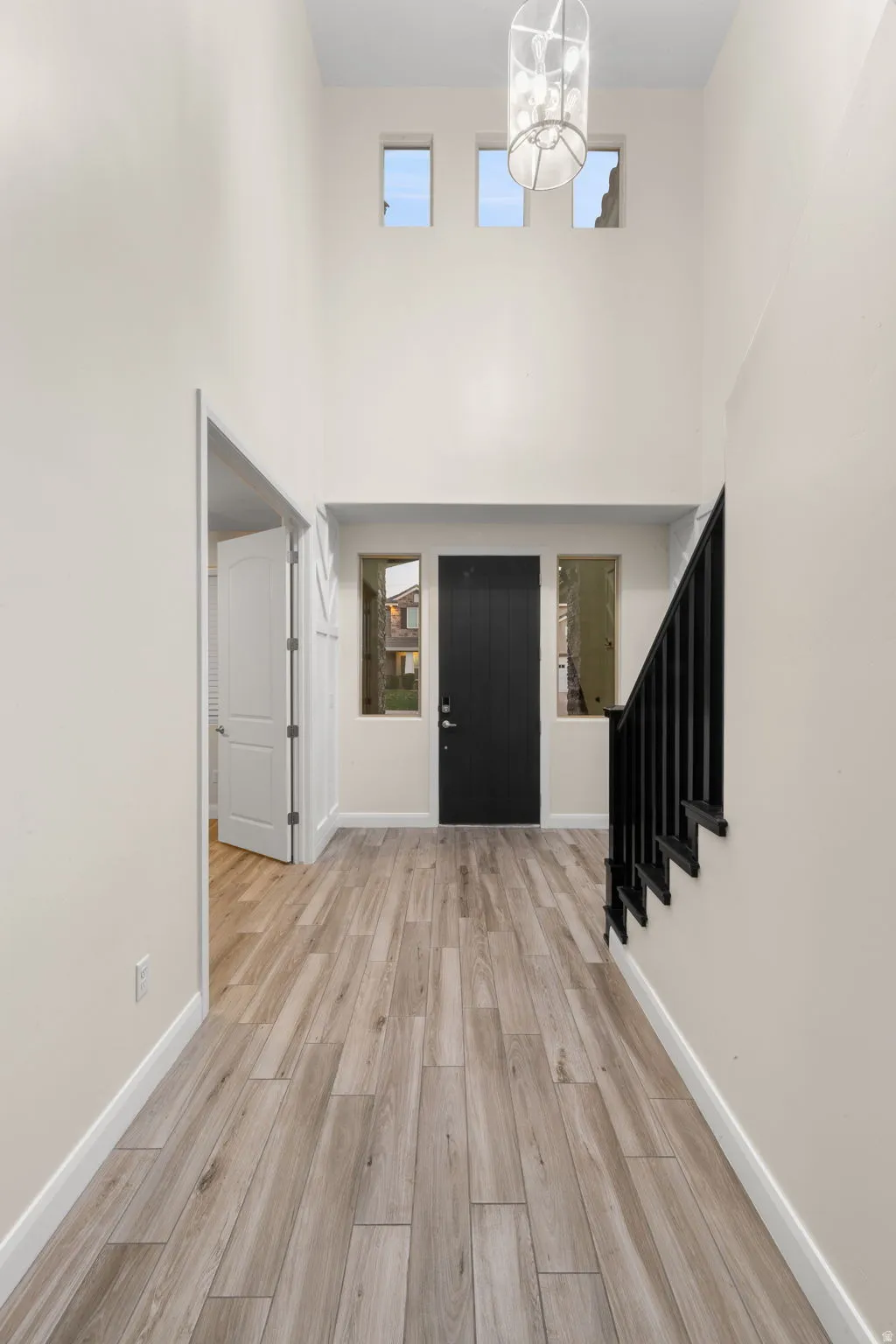 Entryway featuring stairs, light wood-style flooring, and a towering ceiling