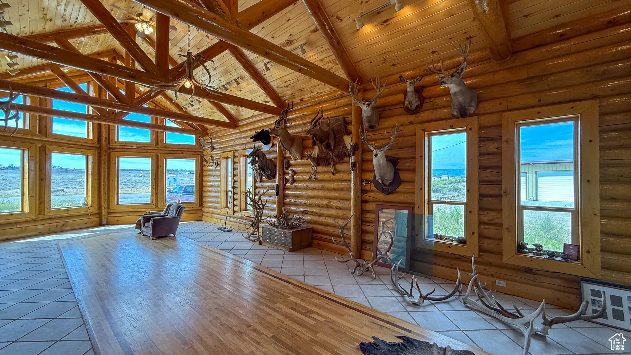 Unfurnished living room with high vaulted ceiling, light tile patterned flooring, a wood ceiling with exposed beams, and a water view