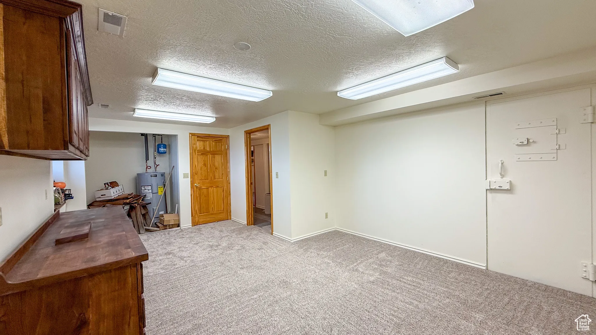 Kitchen featuring a textured ceiling, carpet, and water heater