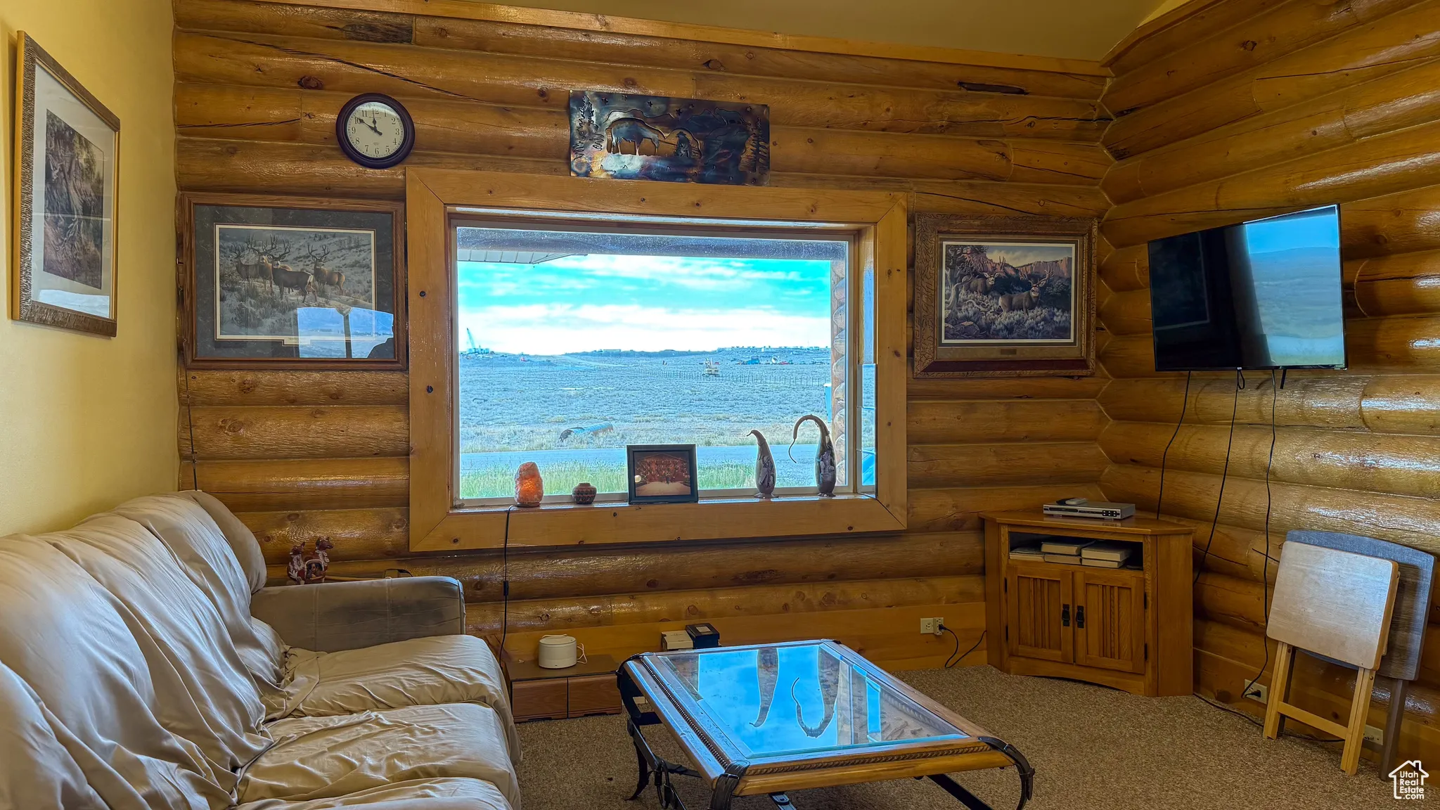 Carpeted living area featuring log walls