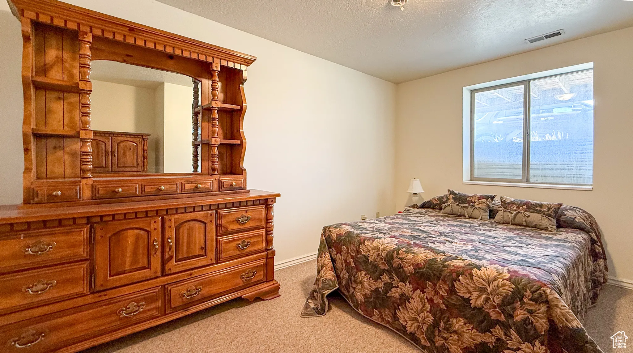 Carpeted bedroom featuring a textured ceiling and baseboards