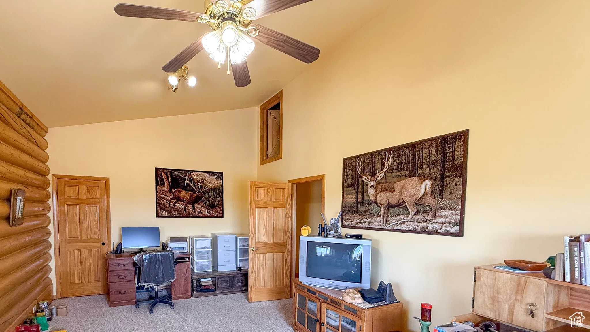 Office area featuring vaulted ceiling, carpet, ceiling fan, and log walls