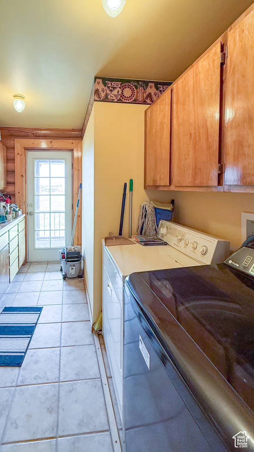 Laundry room with cabinet space, washing machine and dryer, and light tile patterned floors