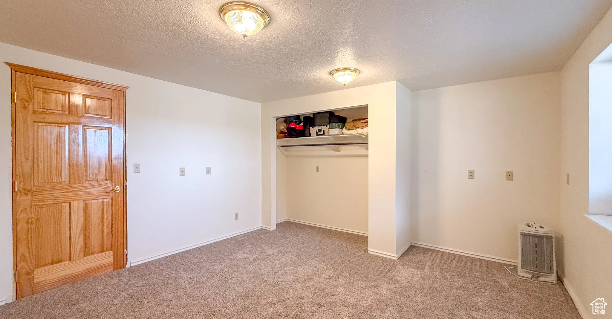 Unfurnished bedroom featuring a textured ceiling, light carpet, and a closet
