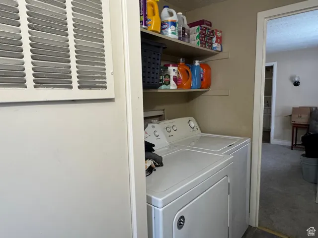 Laundry area with washer and clothes dryer, carpet floors, and a textured ceiling