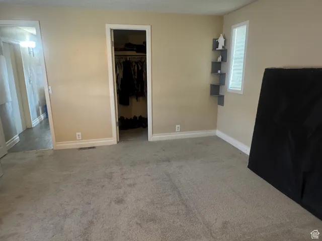Unfurnished bedroom with carpet flooring and a walk in closet