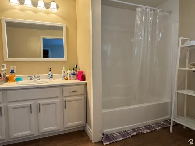 Full bathroom with vanity, shower / bath combo with shower curtain, and wood finished floors