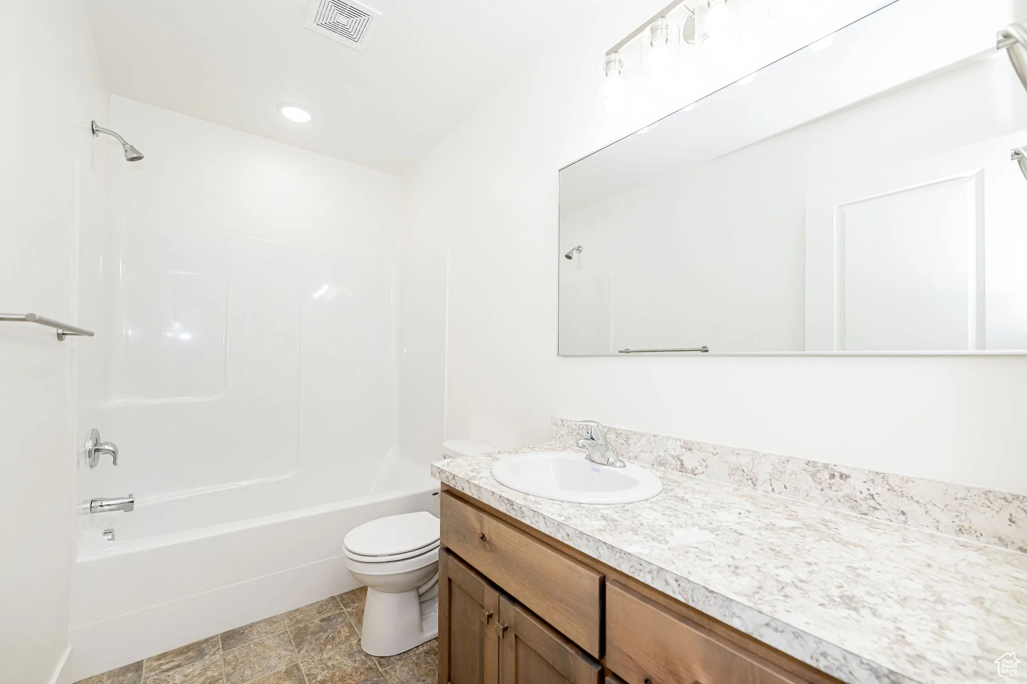Bathroom featuring vanity, bathing tub / shower combination, and stone finish flooring