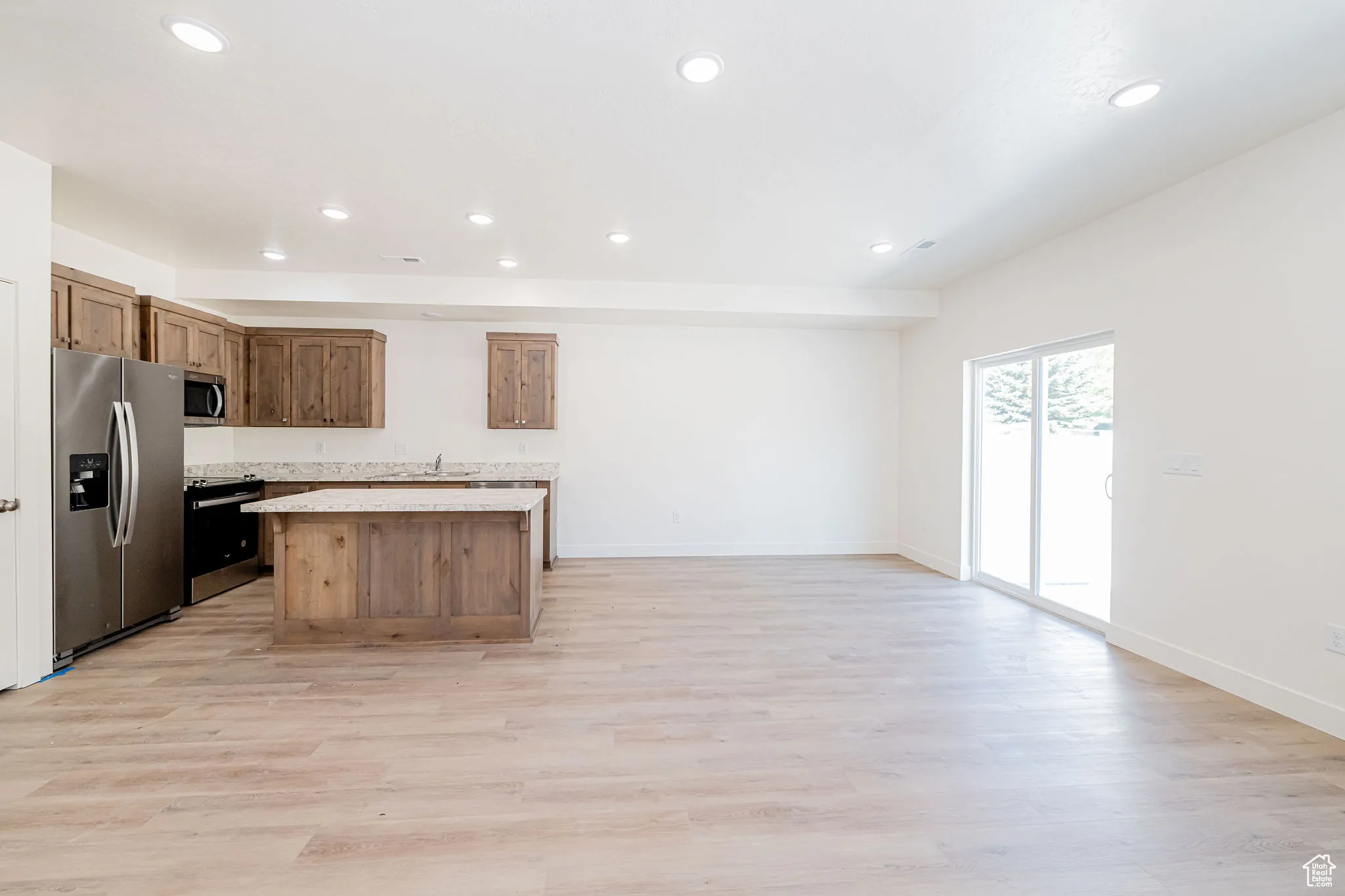 Kitchen with a kitchen island, stainless steel appliances, light countertops, light wood-type flooring, and recessed lighting