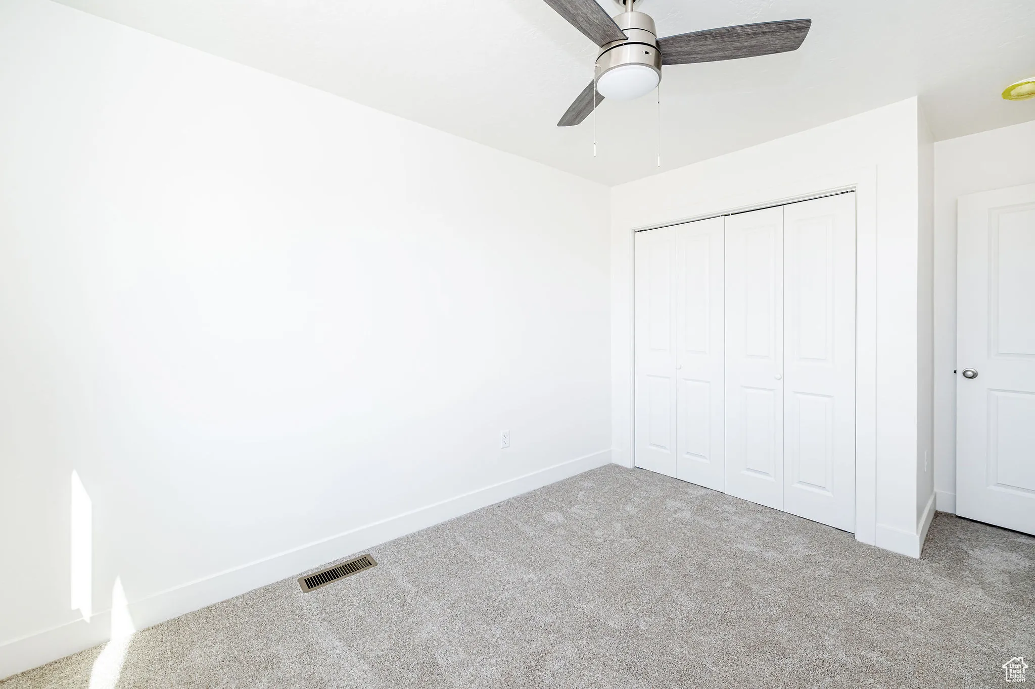 Unfurnished bedroom featuring carpet floors, a closet, and a ceiling fan