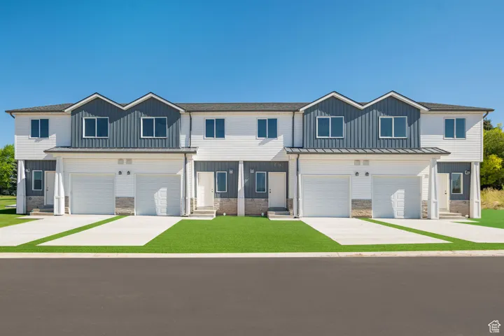 View of front facade with concrete driveway, stone siding, and board and batten siding
