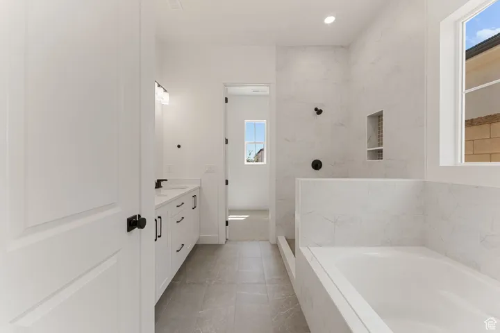 Full bath with vanity, a garden tub, and a walk in shower