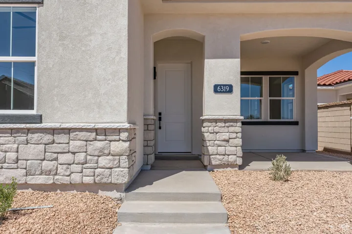 Doorway to property featuring stucco siding and stone siding