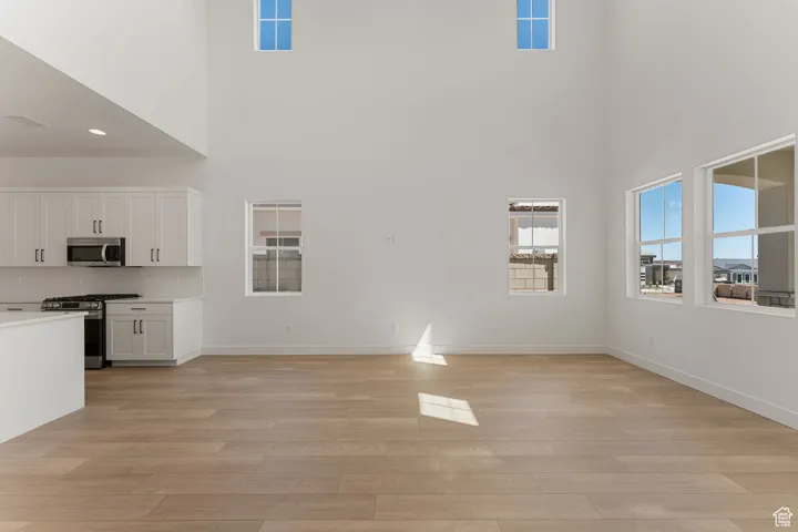 Unfurnished living room with light wood-style floors and baseboards
