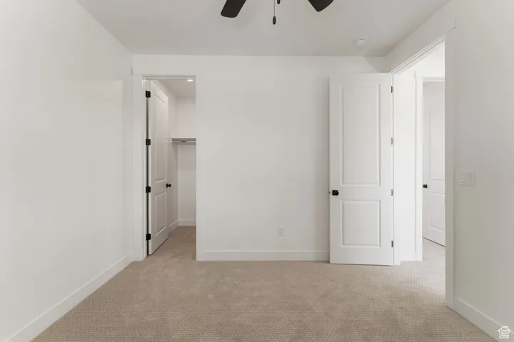 Unfurnished bedroom with carpet floors, a walk in closet, and ceiling fan