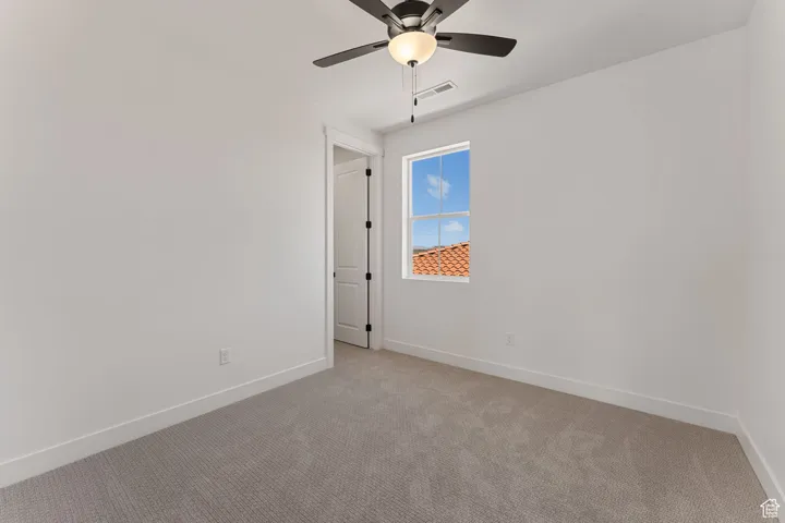 Unfurnished room featuring light carpet and ceiling fan