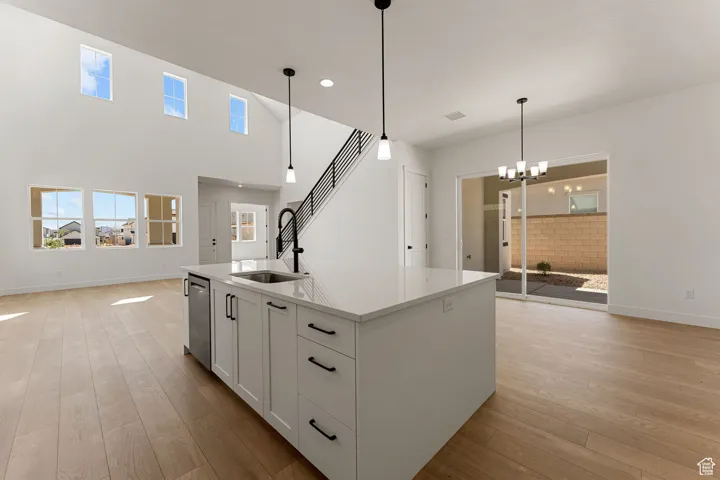 Kitchen with light wood-style floors, open floor plan, white cabinetry, light countertops, and healthy amount of natural light