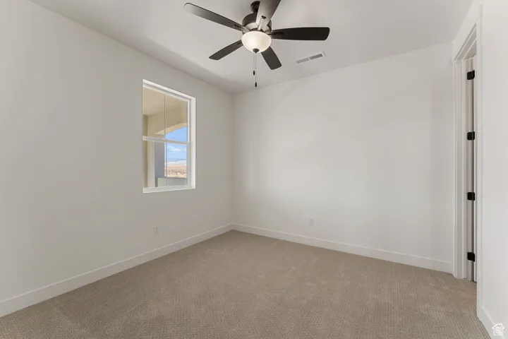 Empty room with light carpet and ceiling fan