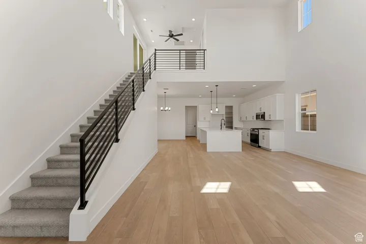 Unfurnished living room with light wood finished floors, stairs, recessed lighting, and ceiling fan