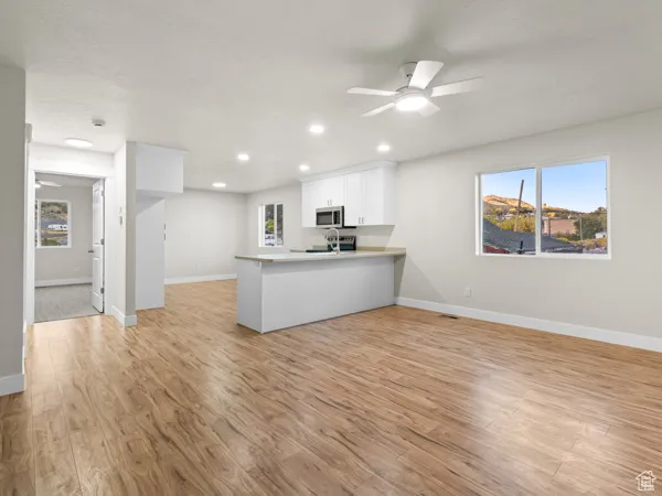 Kitchen with a ceiling fan, open floor plan, a peninsula, white cabinetry, and recessed lighting