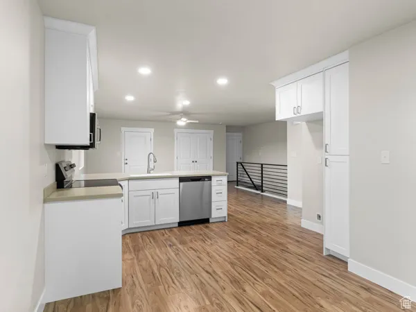 Kitchen with white cabinets, light countertops, recessed lighting, light wood finished floors, and a peninsula