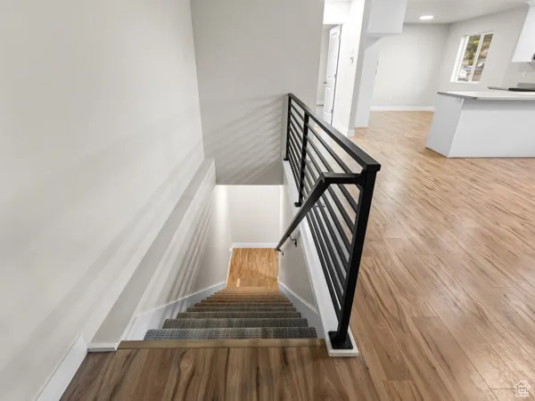 Staircase with wood finished floors and recessed lighting
