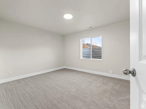 Empty room with light carpet and baseboards